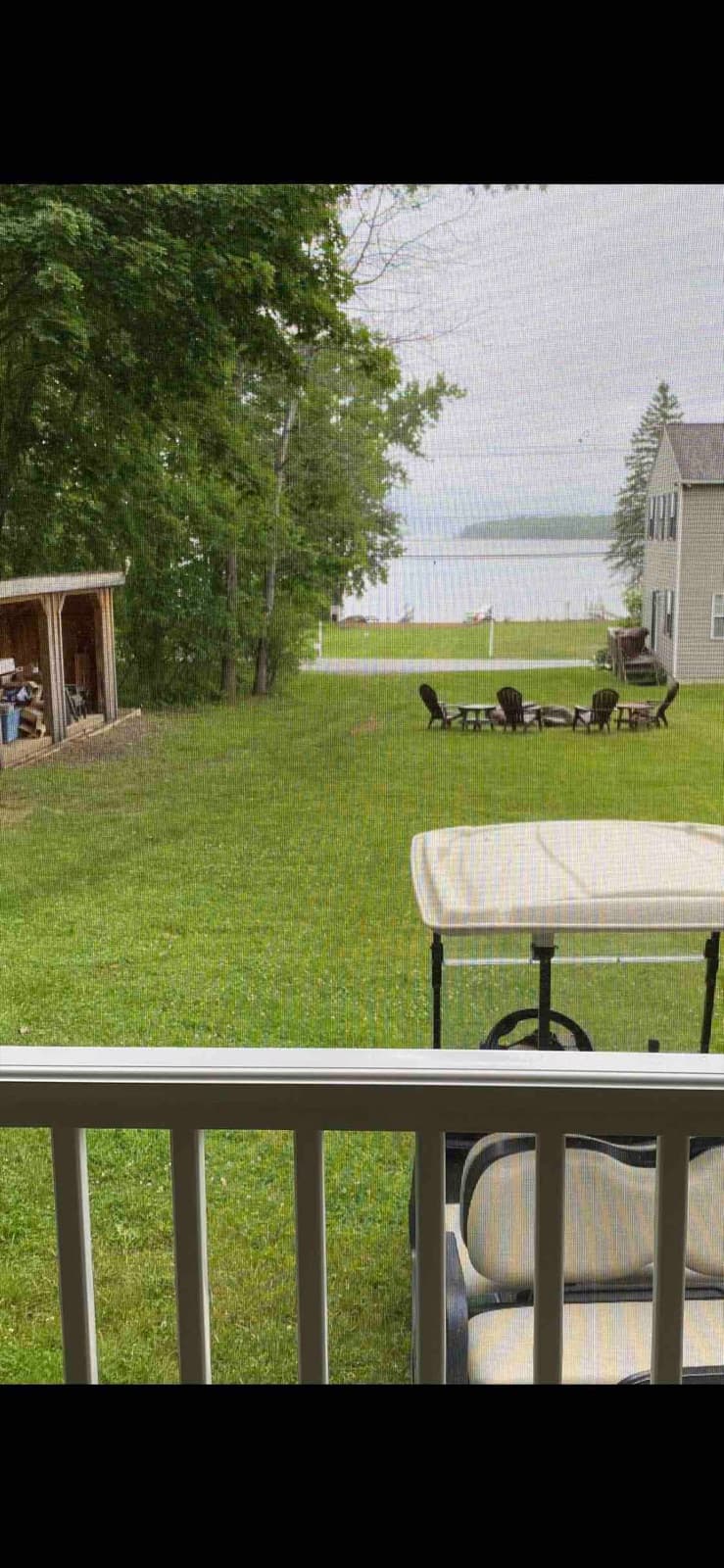 View from the screened porch — the fire pit, big yard and lake beyond