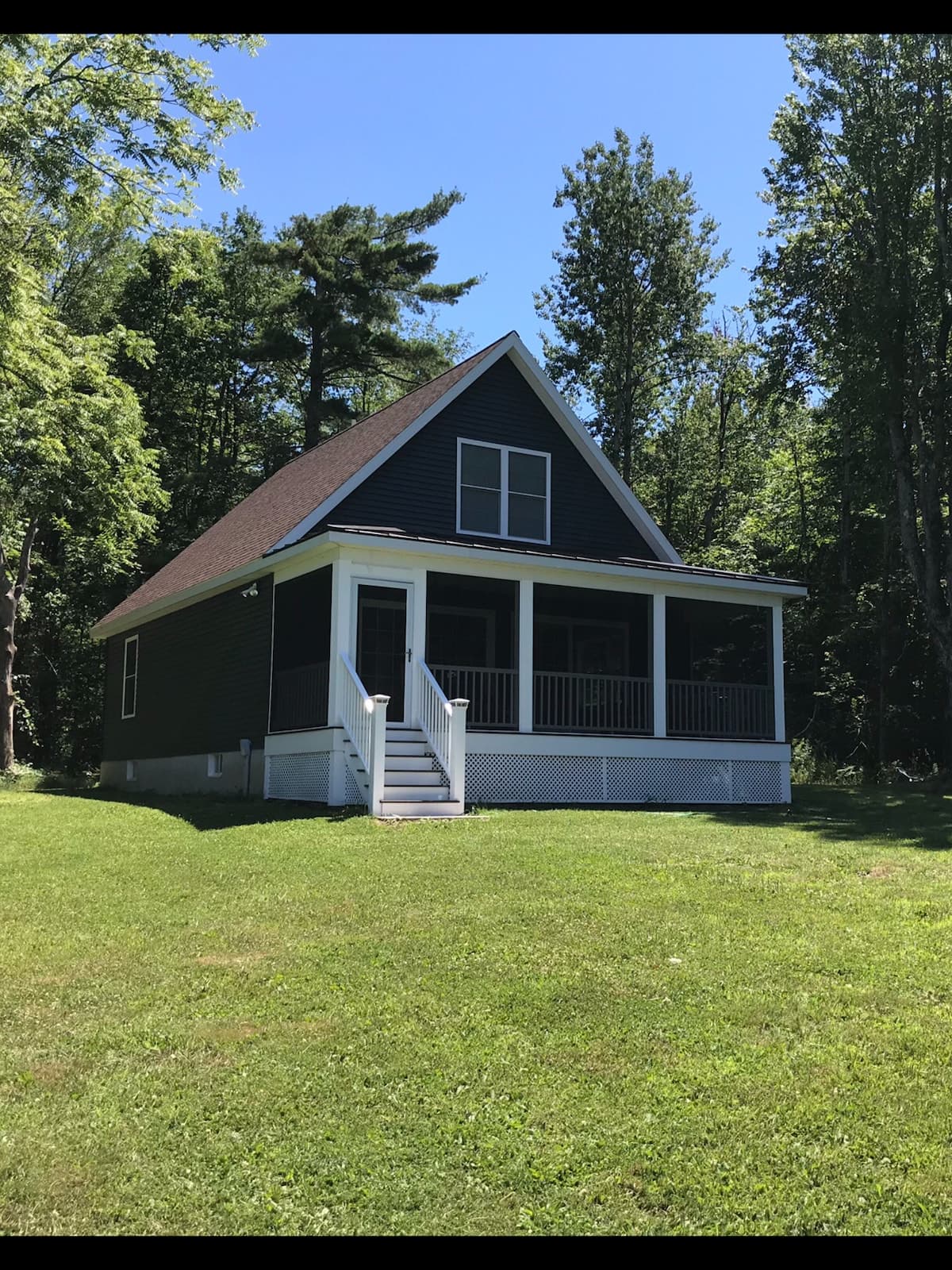 Our lakefront guesthouse in North Broadalbin — a charcoal cabin with a screened porch in a wooded clearing